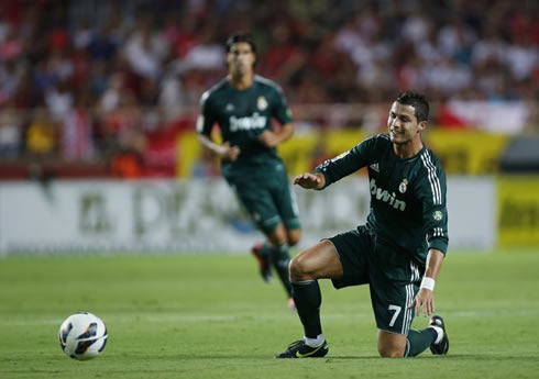Cristiano Ronaldo with one knee on the ground, looking at the ball getting away from him, in Sevilla vs Real Madrid, in 2012