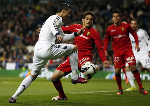 Cristiano Ronaldo dribbling a defender near the penalty area, as the ball bounces in front of him