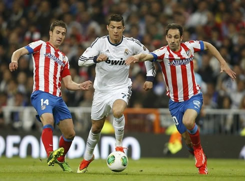 Cristiano Ronaldo dribbling past two Atletico Madrid defenders, Gabi and Juan Fran, in a game for Real Madrid at the Copa del Rey final of 2013
