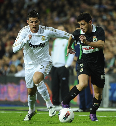 Cristiano Ronaldo sprinting side by side with a defender, chasing the ball in a Real Madrid game in 2012