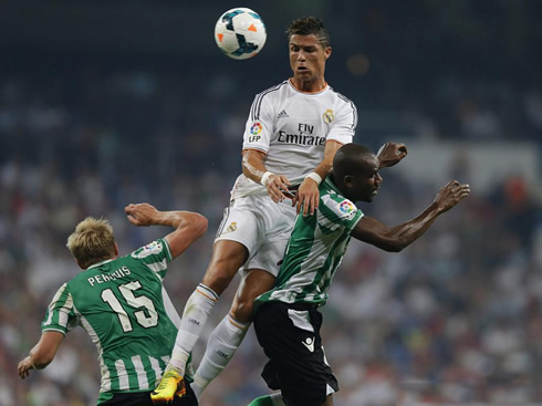 Cristiano Ronaldo rising above two Betis defenders, to head the ball towards goal