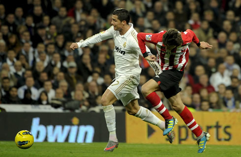 Cristiano Ronaldo sprinting but being pulled by a defender, in Real Madrid 2011-2012