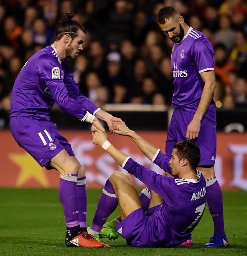 Gareth Bale pulls Cristiano Ronaldo from the ground as Benzema observes