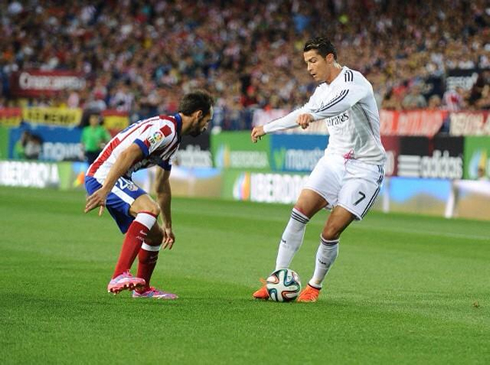 Cristiano Ronaldo trying to dribble a defender in Atletico vs Real Madrid in 2014