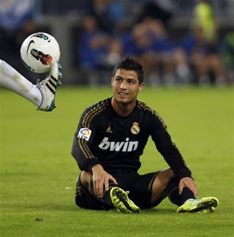 Cristiano Ronaldo stretches his legs while sitted on the pitch and looking to his opponent