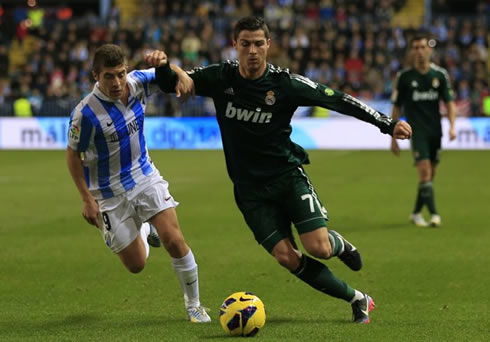Cristiano Ronaldo using his arm to protect the ball from a defender, in a Real Madrid match in 2012-2013