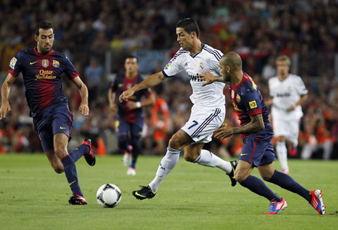 Cristiano Ronaldo being pulled by Daniel Alves and protecting the ball, in Barça vs Real Madrid in 2012