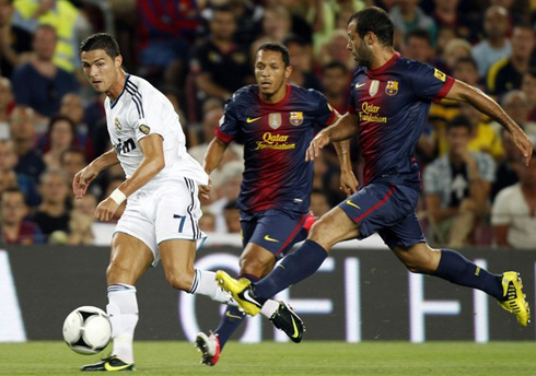 Cristiano Ronaldo making a right-foot cross, with Adriano and Mascherano watching him closely, in Barcelona vs Real Madrid for the Spanish Supercup 2012-2013
