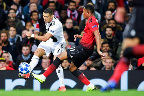 Ronaldo crossing the ball near the sideline, with Martial defending him