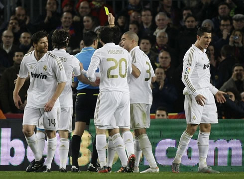 Cristiano Ronaldo turning his back at the referee, while being shown the yellow card, with Pepe, Higuaín, Granero and Xabi Alonso also protesting