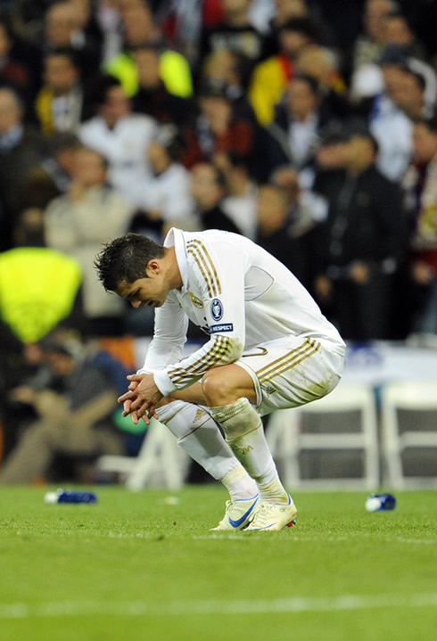 Cristiano Ronaldo in squatting position, thinking about what went wrong for Real Madrid to lose against Bayern Munich in the penalties shootout