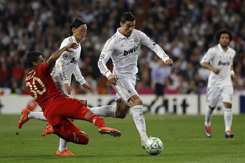 Cristiano Ronaldo sprinting with the ball but about to get tackled by Luis Gustavo from Bayern Munich, in 2012