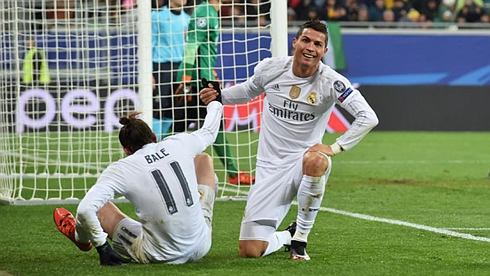 Cristiano Ronaldo smiles as he helps Gareth Bale standing up