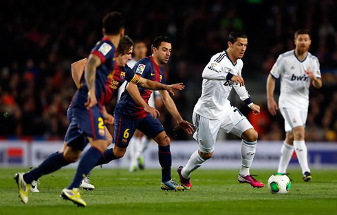 Cristiano Ronaldo running with the ball in Barcelona vs Real Madrid, while being chased by Xavi and Puyol, in 2013