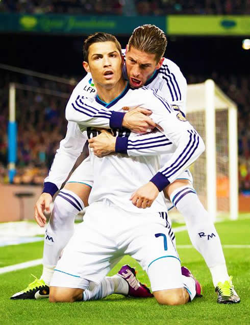 Cristiano Ronaldo on his knees while Sergio Ramos hugs him from behind, during a goal celebration in Barcelona vs Real Madrid in 2013