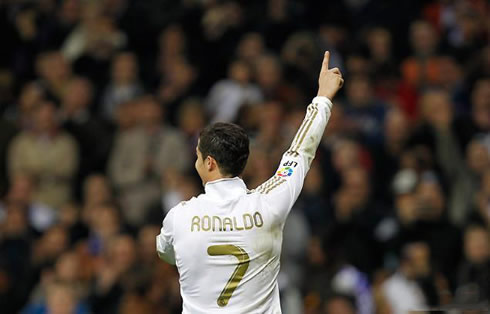 Cristiano Ronaldo smiles and stretches his arm to point at someone in the crowd