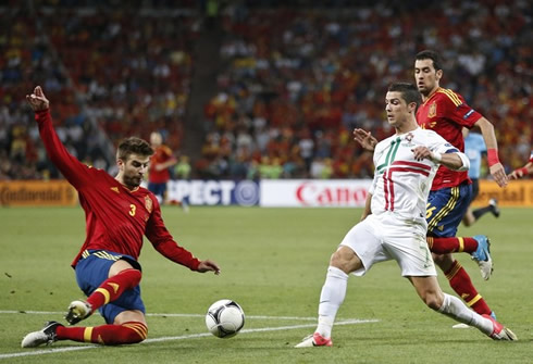 Cristiano Ronaldo trying to avoid a sliding tackle from Gerard Piqué, in Portugal vs Spain in the EURO 2012