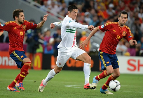 Cristiano Ronaldo running with the ball between Barcelona new signing, Jordi Alba, and Sergio Busquets, in Portugal vs Spain at the EURO 2012