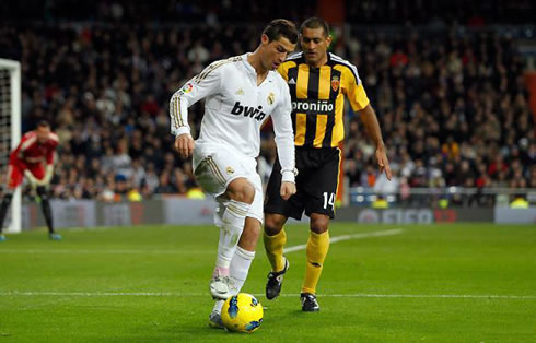 Cristiano Ronaldo stomping the ball and protecting it from the defender, in Real Madrid in 2012