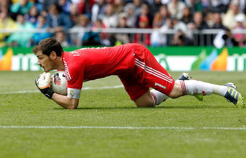 Iker Casillas wearing a red uniform and grabbing the ball during a Real Madrid match for La Liga in 2012