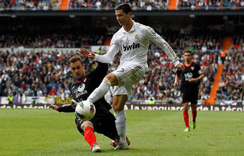 Cristiano Ronaldo being tackled hard by a Sevilla defender, in a Real Madrid game for La Liga in 2012
