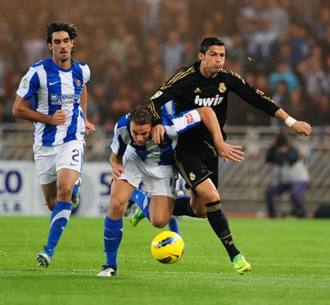 Cristiano Ronaldo fights for the ball with a Real Sociedad defender pushing him
