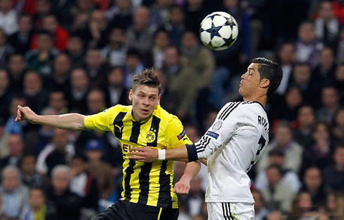 Cristiano Ronaldo jumping higher than a Borussia Dortmund opponent and heading the ball during the game for Real Madrid in 2013