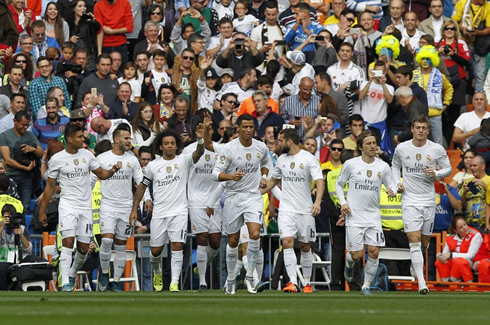 Cristiano Ronaldo walks away from his teammates, as Real Madrid players gather around each other to celebrate a goal at the Santiago Bernabéu