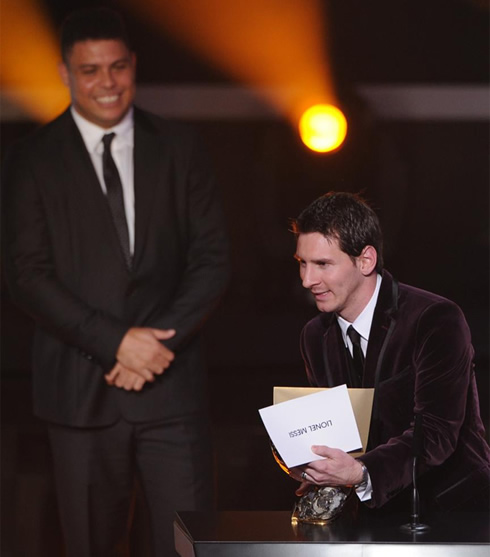 Messi holding the trophy with Ronaldo smiling behind him at FIFA Balon d'Or 2011