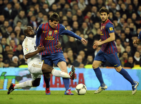 Lass Diarra tackling Lionel Messi from behind with Cesc Fabregas close, in a Real Madrid vs Barcelona game, played in 2011/2012