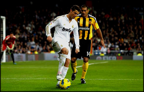 Cristiano Ronaldo holding and protecting the ball from a defender, in Real Madrid 2012
