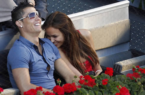 Cristiano Ronaldo laughing while wearing sunglasses, with Irina Shayk also smiling next to his shoulder