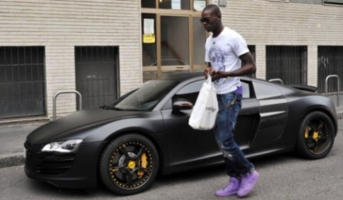 Mario Balotelli with purple shoes leaving his car, a black Audio R8, in 2012