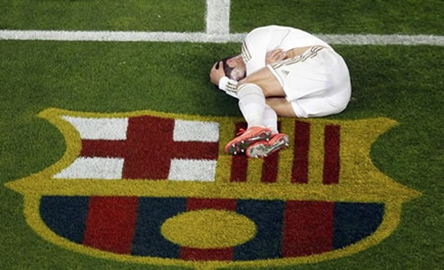 Cristiano Ronaldo on the ground, in a fetal position, near Barcelona's badge and symbol in the Camp Nou grass