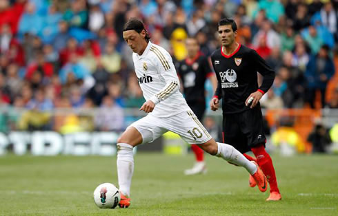 Mesut Ozil running with the ball, while José Antonio Reyes chases him, in Real Madrid vs Sevilla for La Liga in 2012