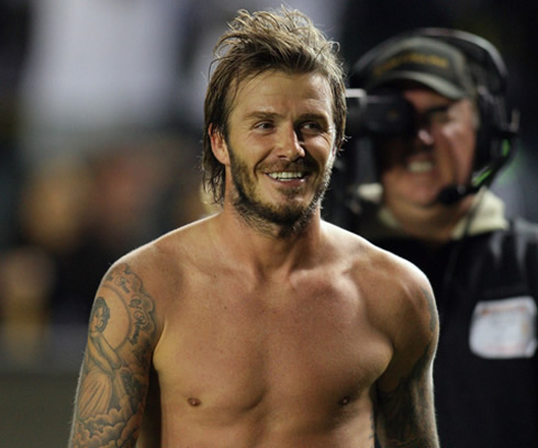 David Beckham with a big beard and shirtless, smiling to the public