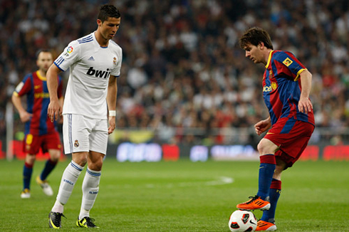 Cristiano Ronaldo looking at Lionel Messi controlling the ball, in Barcelona vs Real Madrid, in 2012