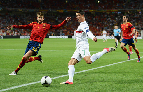 Gerard Piqué about to make a sliding tackle to Cristiano Ronaldo, in a Spain vs Portugal match at the EURO 2012