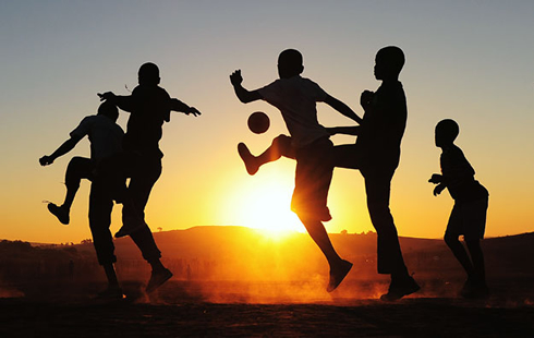 Kids playing soccer during the sunset