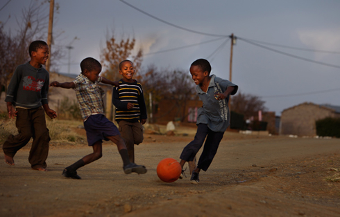 Young kids and children playing football/soccer, in the streets