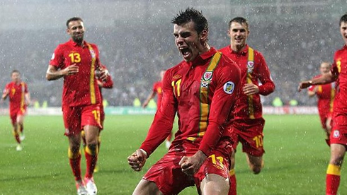 Gareth Bale celebrating a goal with his Welsh teammates, during a rainy football match