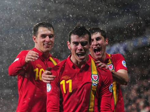 Gareth Bale smiling to the cameras, with two other Welsh National Team players