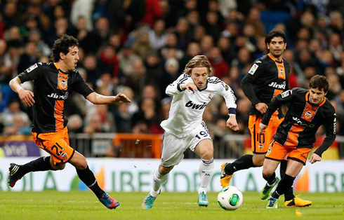 Luka Modric carrying the ball on the pitch, in a fast pace, during a match for Real Madrid, in 2013
