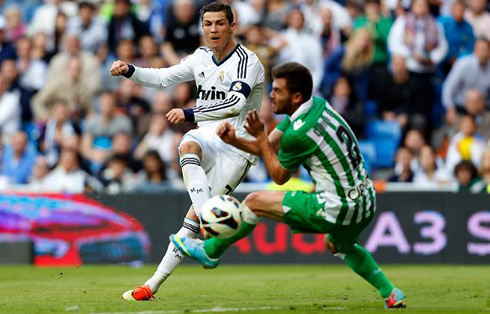 Cristiano Ronaldo shooting a football past a Betis defender, in a game for La Liga