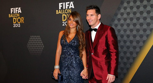 Lionel Messi in a red suit, next to Antonella Roccuzzo in the FIFA Ballon d'Or 2013 ceremony
