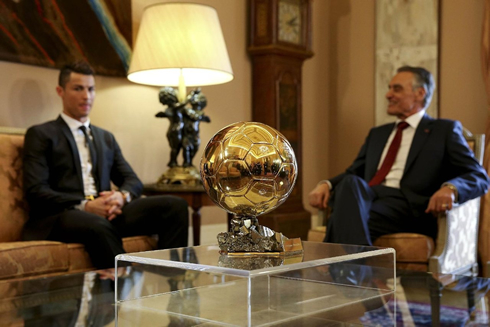 Cristiano Ronaldo and Cavaco Silva talking, with the FIFA Ballon d'Or in the center of the room