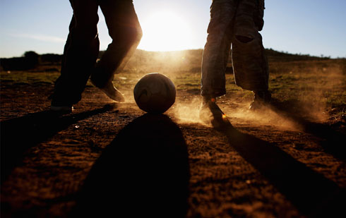 Children playing football barefoot