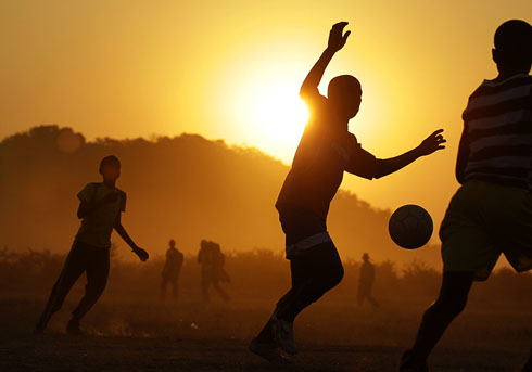 Children playing football in the sunset
