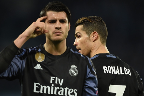 Alvaro Morata pointing to his head as Ronaldo walks behind him