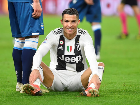 Cristiano Ronaldo sits down on the pitch and smiles